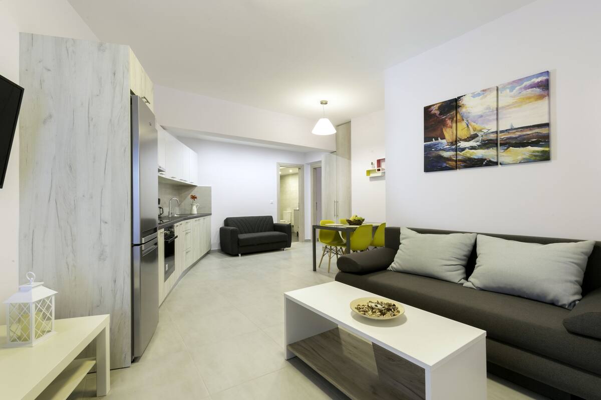 A modern living space with a kitchen, dining area, and a sofa.