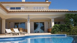 A two-story house with a swimming pool, lounge chairs, and a covered patio area. - Villa Mediterranea, Urb Rio de Oro (Calonge)