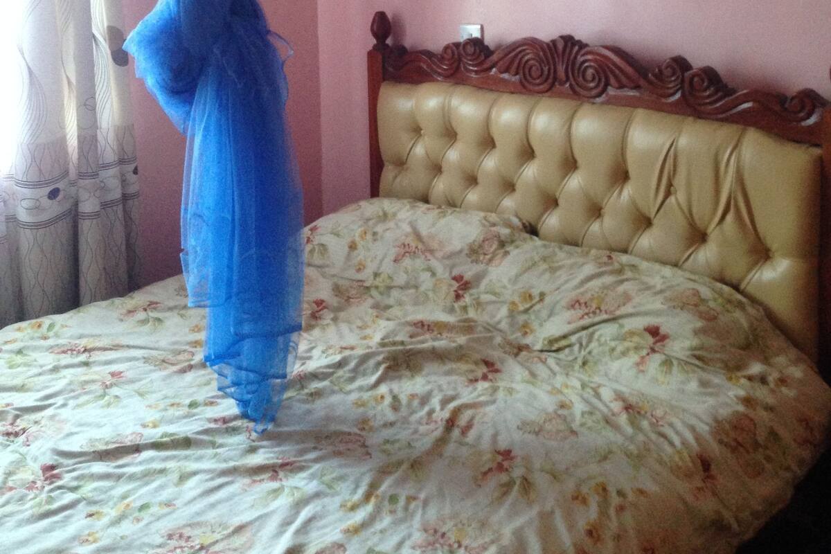 A bedroom with a bed, a canopy, a floral bedspread, and a wooden headboard.
