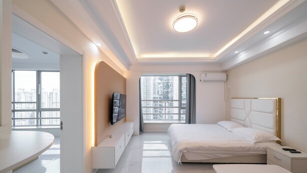 Een moderne hotelkamer met een bed, nachtkastje en een televisie aan de muur.