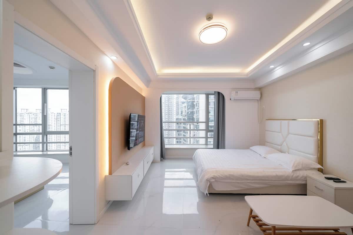 Una habitación de hotel moderna con cama, mesita de noche y televisor en la pared.