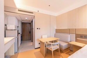 A modern hotel room with a kitchenette, a dining area, and a seating area.