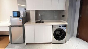 Een kleine keuken met een magnetron, spoelbak en wasmachine.