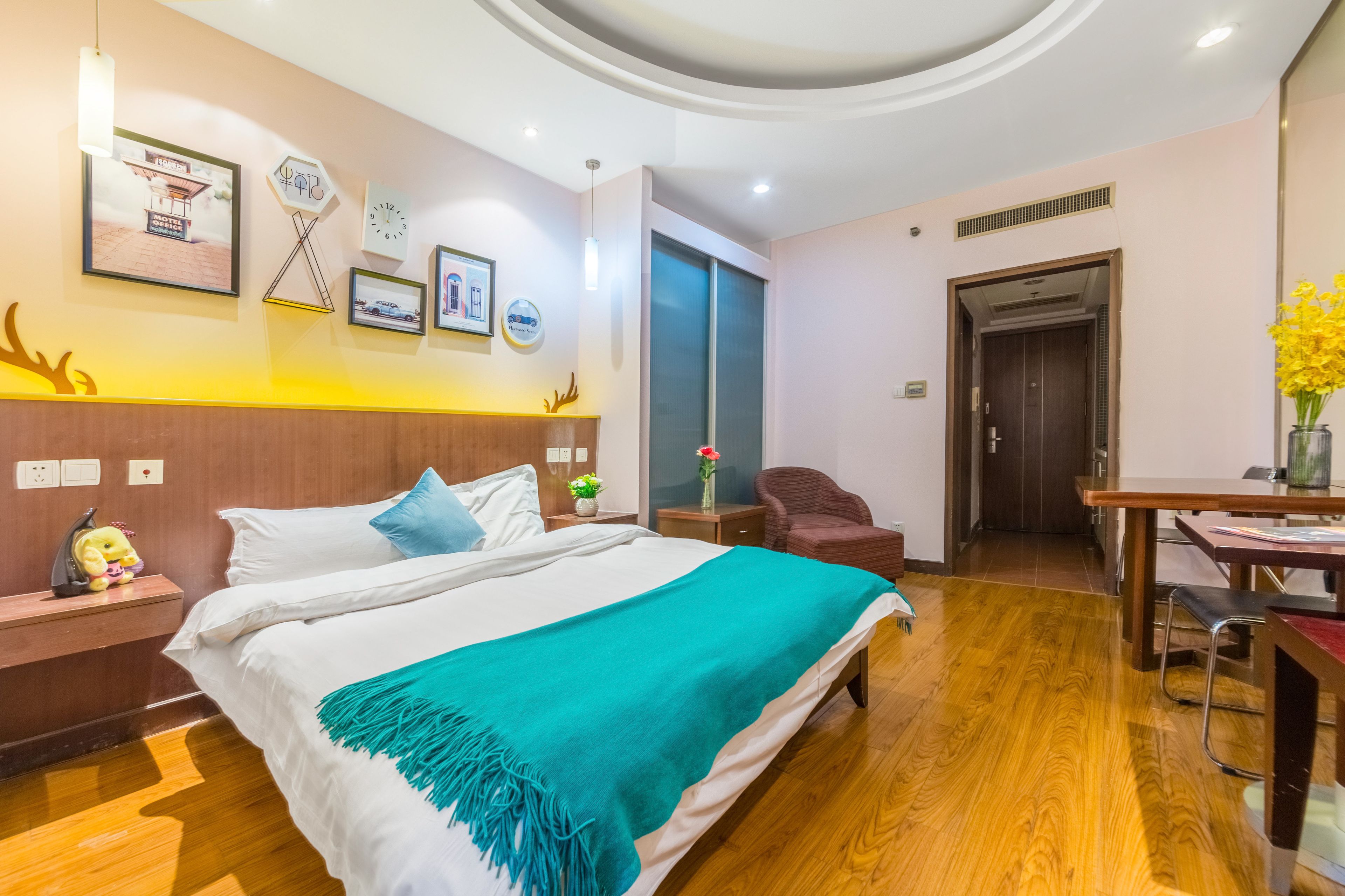 A hotel room with a bed, a desk, a chair, and a small table.