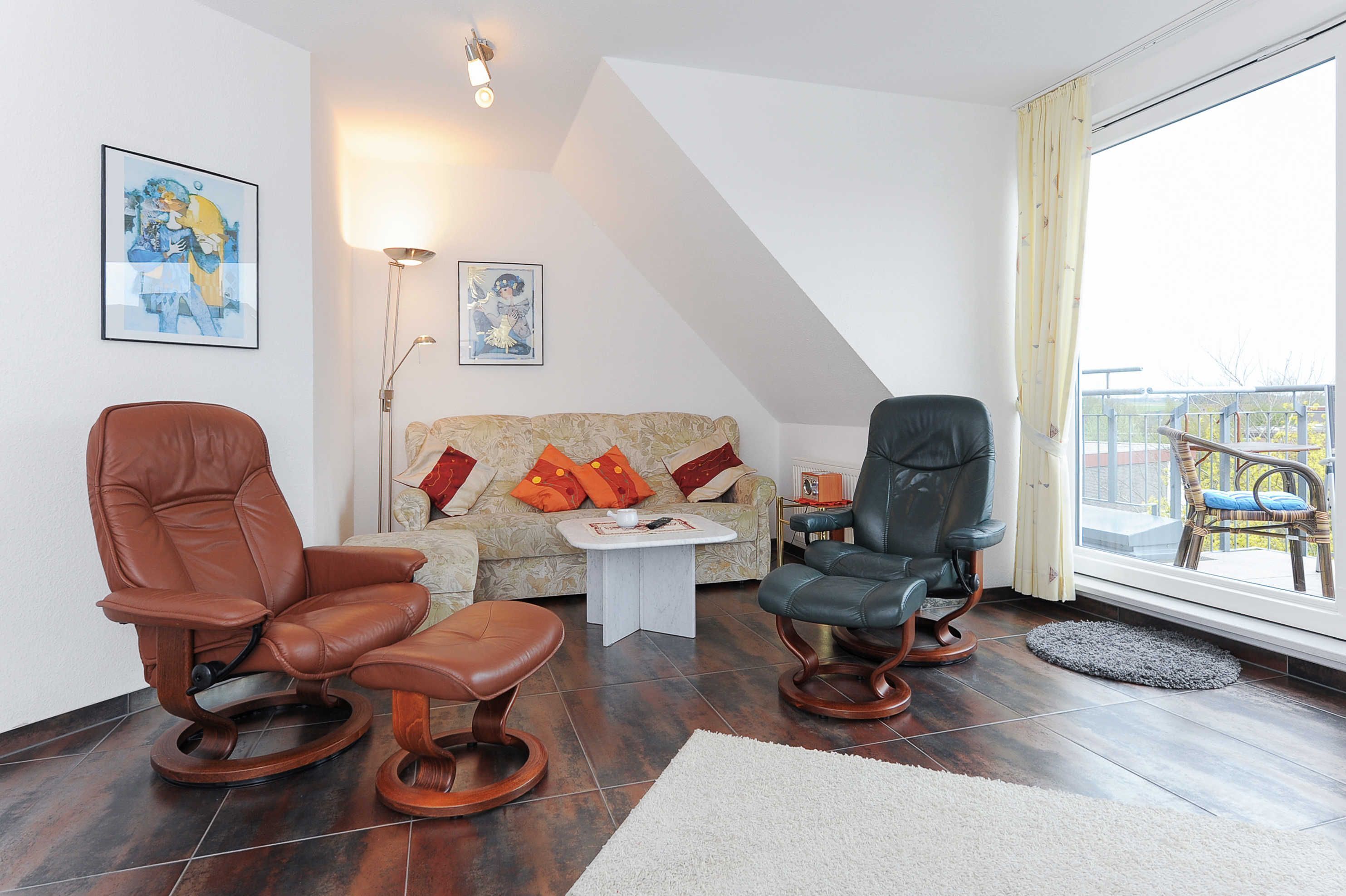 A living room with a sofa, two leather chairs, a coffee table, and artwork on the walls.