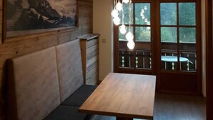 A wooden interior with a bench, a table, a hanging light fixture, and a window with a view. - Schrofenstube in the - Alpinrefugium Haus am Anger (Jungholz)