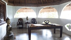 A room with a table, chairs, a Buddha statue, and a heart-shaped decoration. - Iris Island Eco Resort (Busuanga)