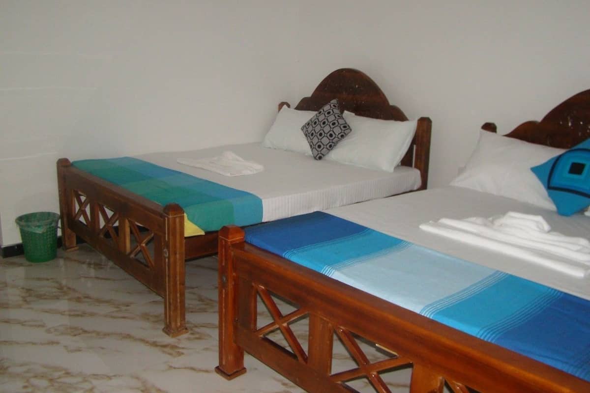 Two wooden beds with headboards, a green trash bin, and a blue and white striped bedspread.