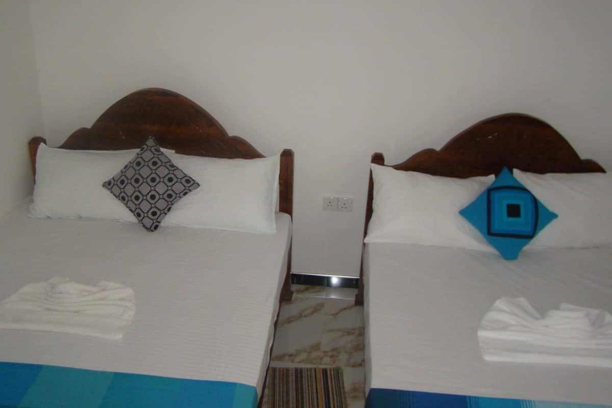 Two single beds with wooden headboards, white linens, and patterned pillows.