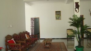 A living room with a sofa set, a coffee table, a potted plant, and a framed picture on the wall. - Nadun Rest (Polonnaruwa)