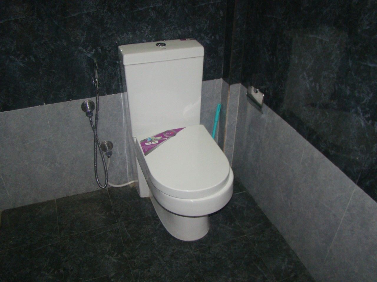 Un baño con inodoro, ducha y secador de manos.