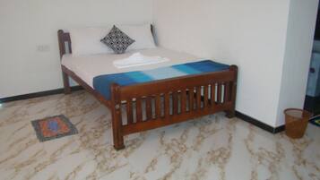 Una cama individual con cabecera de madera, colchón blanco y manta azul.