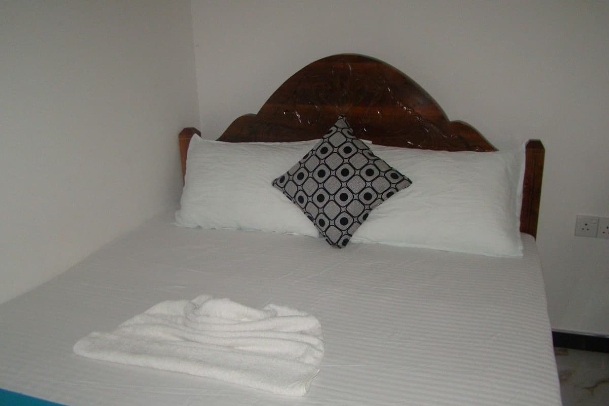 A neatly made bed with a patterned pillow and a folded towel on the bed.