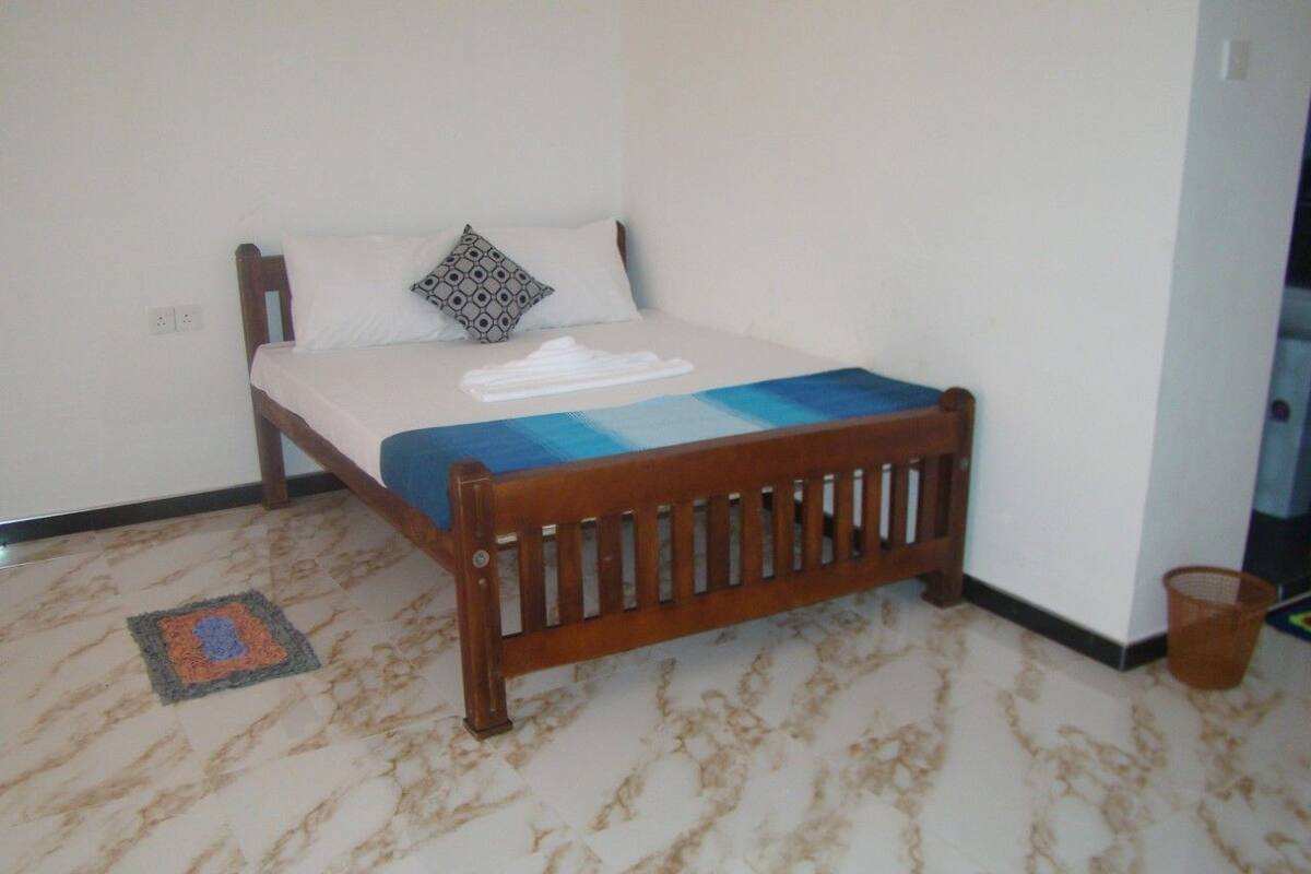 A single bed with a wooden headboard, a white mattress, and a blue blanket.