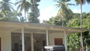 A covered outdoor area with a red auto-rickshaw parked in front. - Nadun Rest (Polonnaruwa)