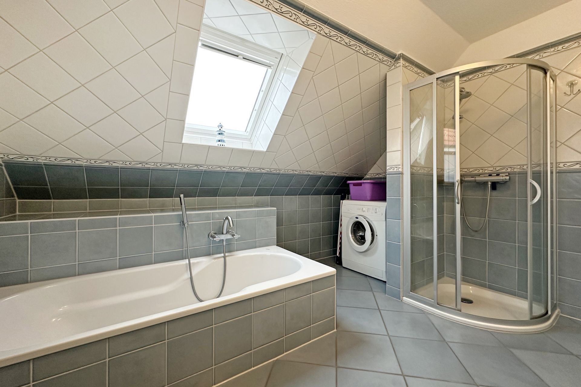 A modern bathroom with a bathtub, a shower, and a washing machine.