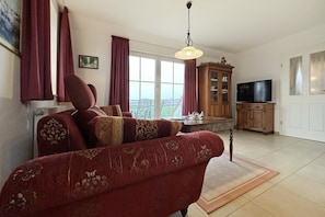 Ein Wohnzimmer mit einer Couch, einem Fernseher und einem Schrank.