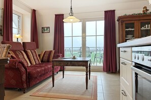 Una sala de estar con sofá, una mesa de comedor y una zona de cocina con horno.