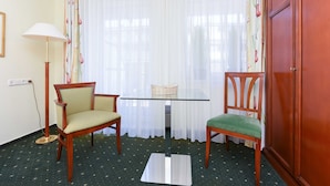 A room with a glass table, two chairs, a lamp, and a wardrobe. - Apartment Aurelia - Apartments in the North Sea Garden Park (Esens)