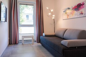 Un salon moderne avec un canapé, un petit banc blanc et une lampe sur pied.