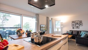 Cocina moderna con placa de inducción, encimera de madera y zona de comedor con mesa y sillas.