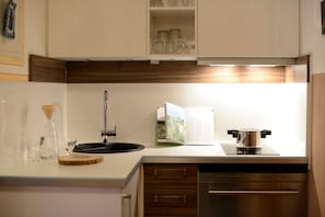 A modern kitchen with a built-in oven, a sink, and a cookbook on the counter.