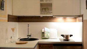 Une cuisine moderne équipée d’un four encastré, d’un évier et d’un livre de recettes posé sur le plan de travail.