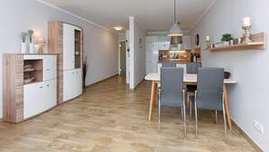 Una cucina moderna con mobili bianchi, un tavolo da pranzo in legno e sedie grigie.