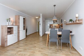 A modern kitchen with white cabinets, a wooden dining table, and grey chairs.
