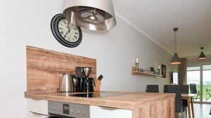 Una cucina moderna con isola in legno, elettrodomestici in acciaio inossidabile e una lampada a sospensione.