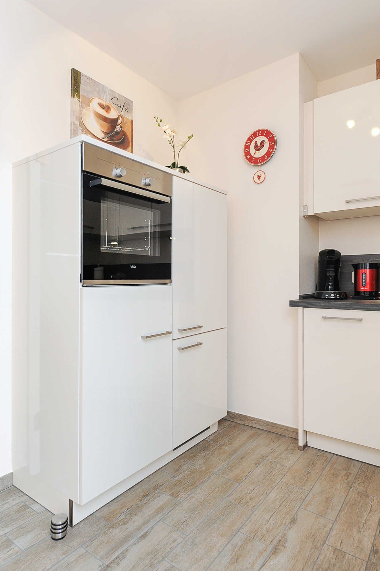 A modern kitchen with white cabinetry, a built-in oven, and a coffee maker on the countertop.