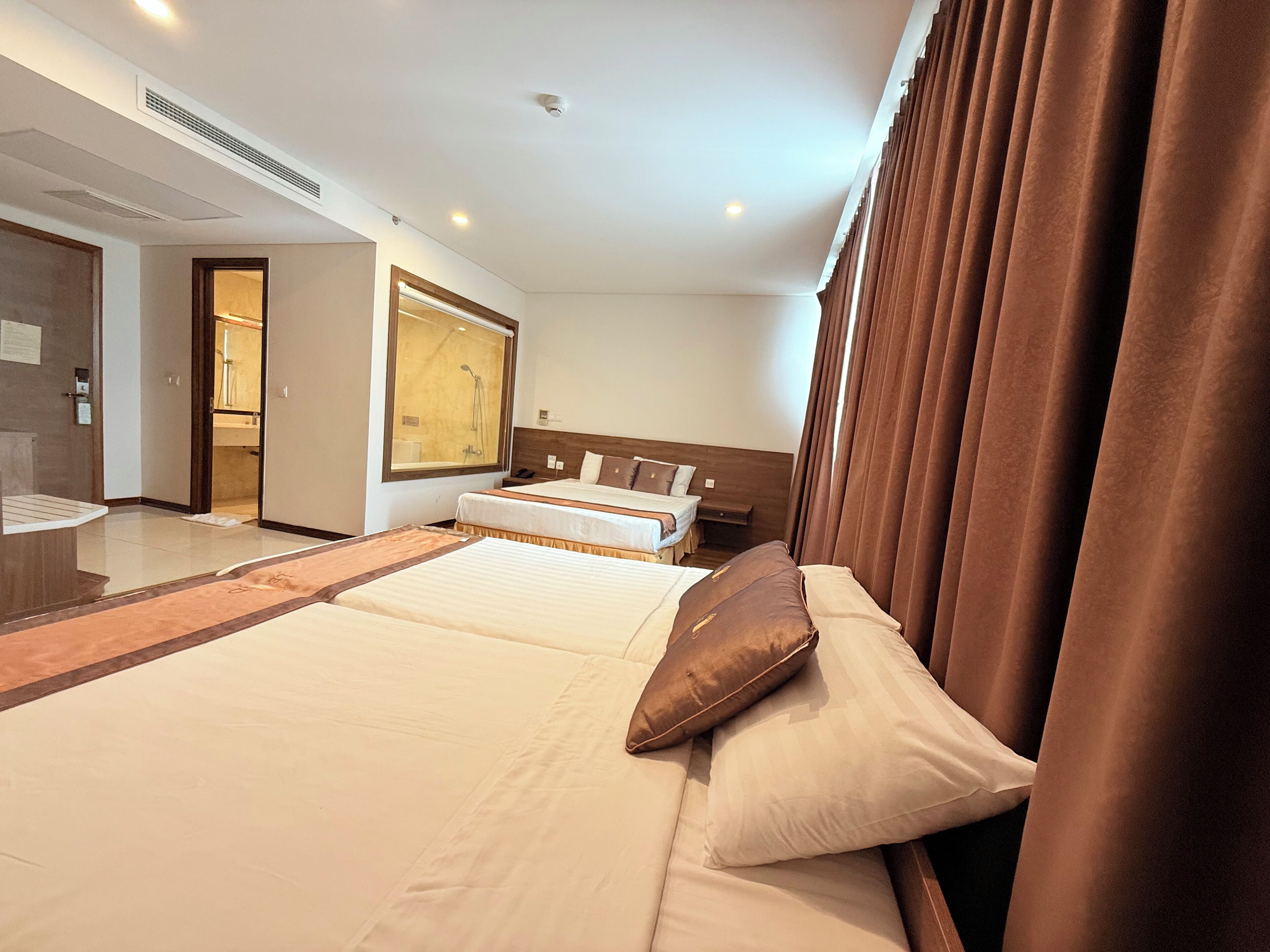 A hotel room with a large bed, a separate sofa, a desk, and a shower area.