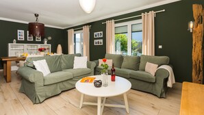 A living room with two green sofas, a white coffee table, and a wooden dining table. - Usedom tourist Karlshagen House Frieda - House Frieda (Karlshagen)