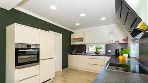 A modern kitchen with white cabinets, a built-in oven, and a black countertop. - Usedom tourist Karlshagen House Frieda - House Frieda (Karlshagen)