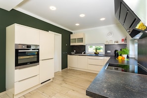 A modern kitchen with white cabinets, a built-in oven, and a black countertop.