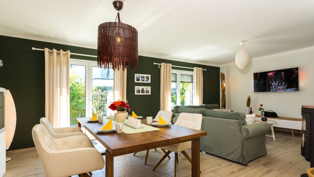 A modern living room with a dining area, a sofa, and a TV mounted on the wall. - Usedom tourist Karlshagen House Frieda - House Frieda (Karlshagen)