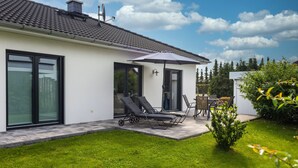 A modern house with a patio area featuring two sun loungers, a table, and an umbrella. - Usedom tourist Karlshagen House Frieda - House Frieda (Karlshagen)