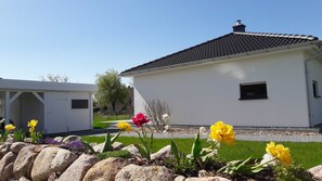 A modern white building with a tiled roof, a small window, and a chimney.