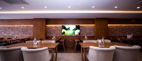 A conference room with a brick wall, wooden tables, and chairs.