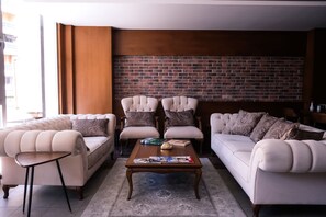 A living room with a brick wall, two sofas, a coffee table, and a side table. - Aripsas Hotel (Giresun)