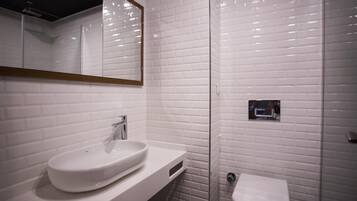 A bathroom with a white sink, a mirror, and a toilet.