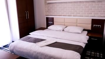 A hotel room with a bed, a wardrobe, a nightstand, and a brick-patterned wall.