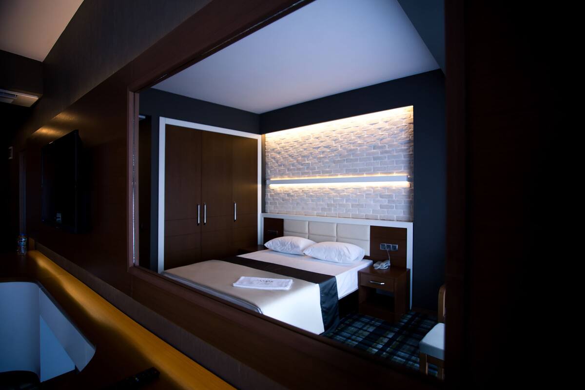 Een moderne hotelkamer met een groot bed, een inbouwkast en een accentmuur met een baksteenmotief.
