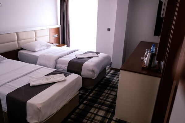 A hotel room with two beds, a small desk, and a check-in counter.