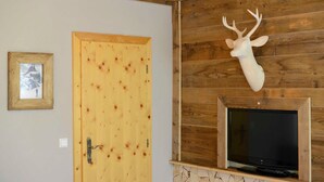 Una porta di legno con una cornice, una testa di cervo appesa al muro e una televisione su uno scaffale di legno.