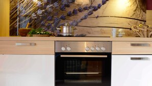 Una cucina con forno a incasso, piano cottura con comandi e parete decorata con motivo floreale.