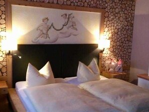 Ein Doppelbett mit weißer Bettwäsche und Kissen, ein Kopfteil mit dekorativer Verkleidung sowie eine Wand mit Steinmuster.
