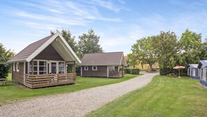 A bungalow-style building with a sloped roof and a porch, surrounded by a well-maintained lawn and a gravel path. - Boeslunde Bed & Breakfast (Skælskør)