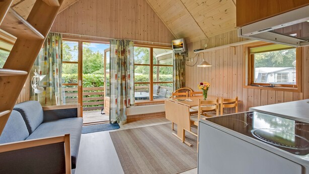A cozy cabin interior with a dining area, kitchen, and seating space. - Boeslunde Bed & Breakfast (Skælskør)