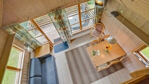 A cozy cabin interior with a sofa, dining table, and large windows. - Boeslunde Bed & Breakfast (Skælskør)